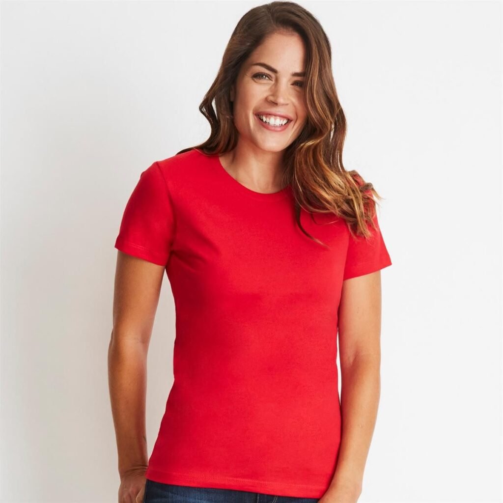 Woman smiling in a red short-sleeve T-shirt, standing against a light background.